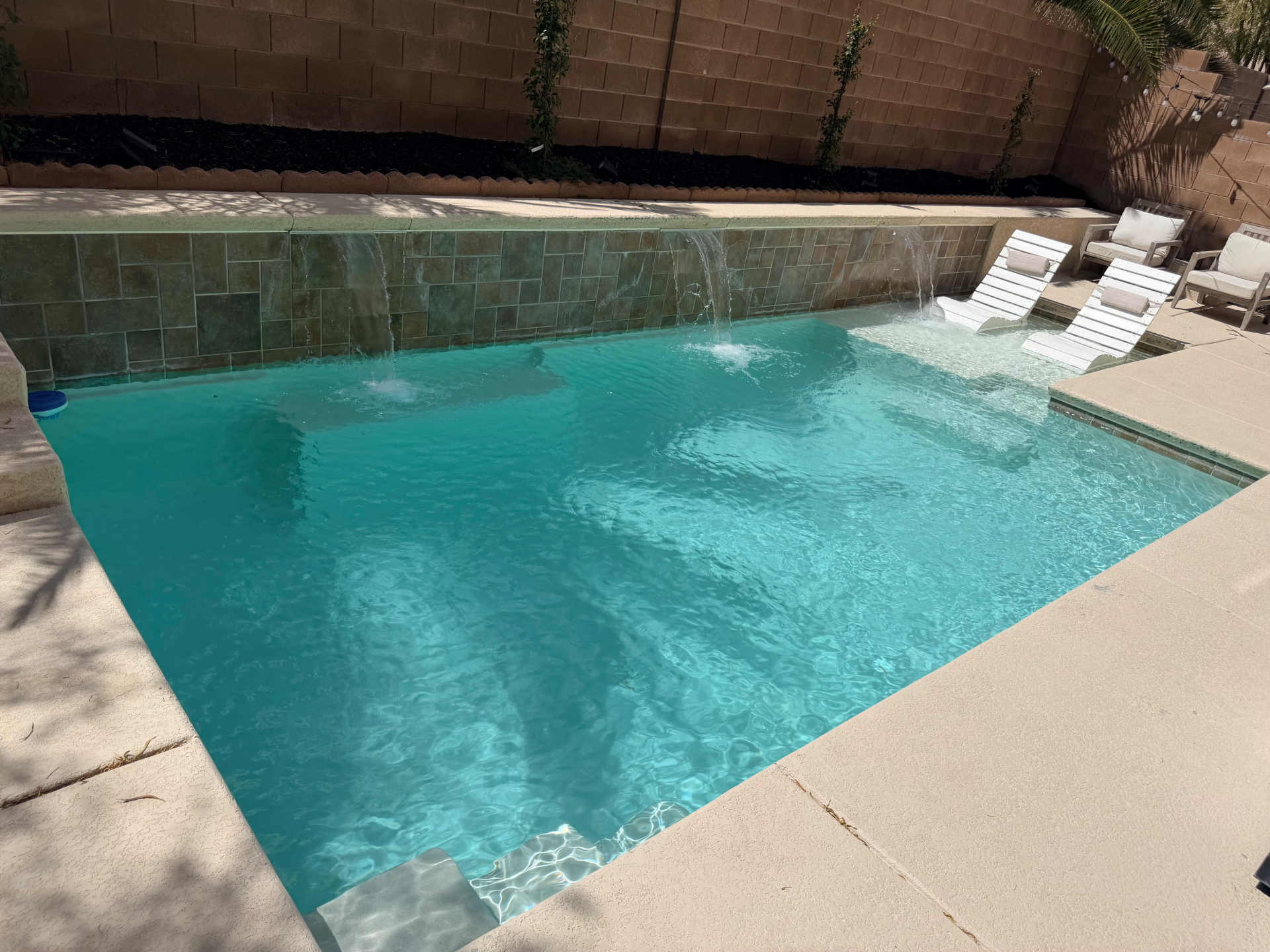 Clean residential pool with a tiled waterfall wall and sun shelf